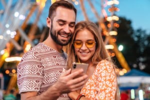 theme park reservations Couple-using-mobile-phone-in-theme-park
